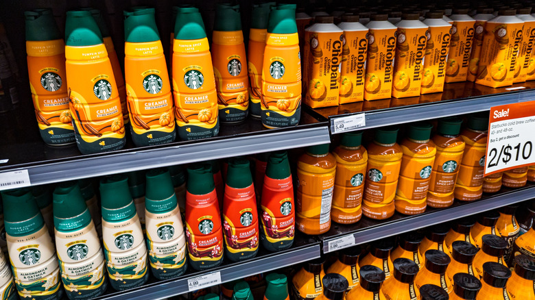 Grocery store shelves full of different pumpkin-flavored coffee creamers and coffee drinks.