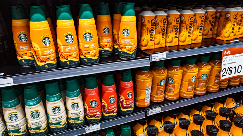 Grocery store shelves full of different pumpkin flavored coffee creamers and coffee drinks.