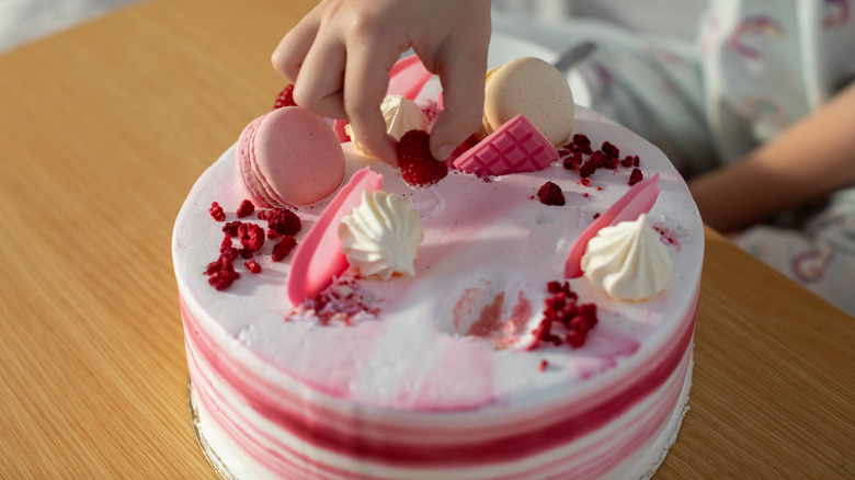 brightly colored pink cake with macarons and dried fruit