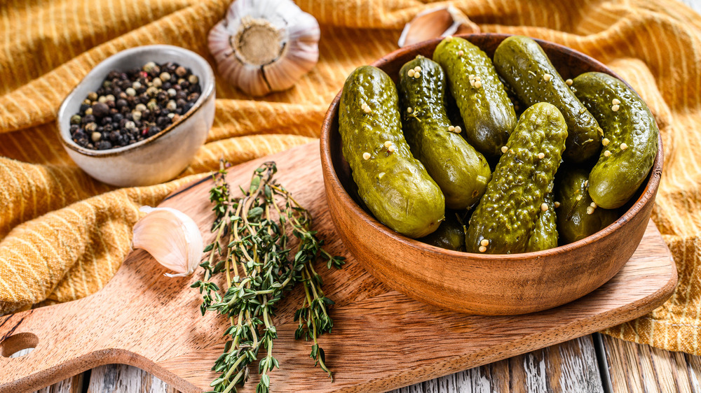 Bowl of pickles on cutting board next to rosemary sprigs