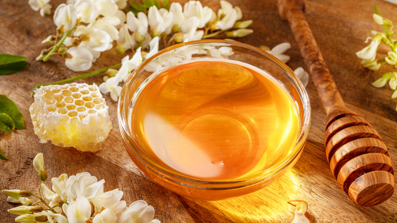 Honey in a glass bowl with a wooden honey stick