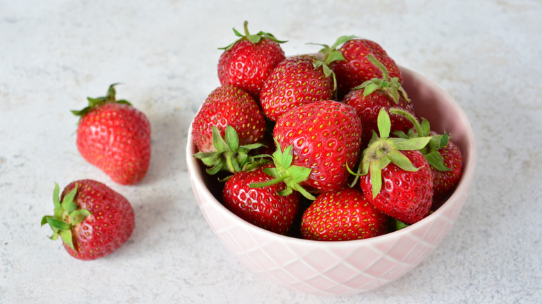 Strawberries in a pink bowl on a marble countertop