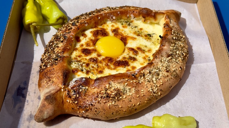 Cardboard box of khachapuri with za'atar on the crust.