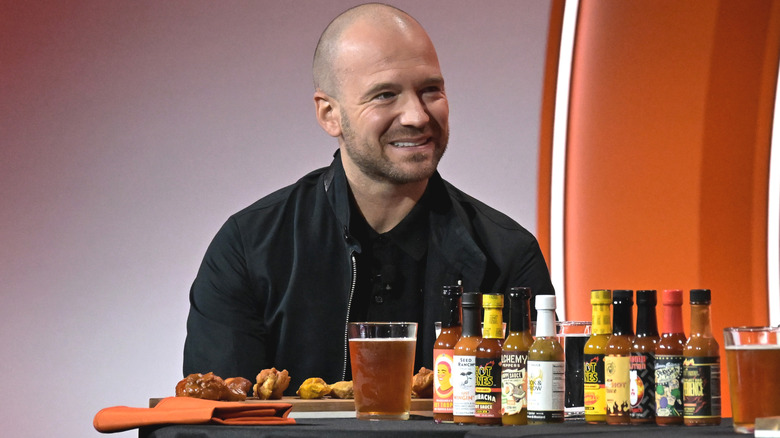 Sean Evans on stage with wings, beer, and hot sauces