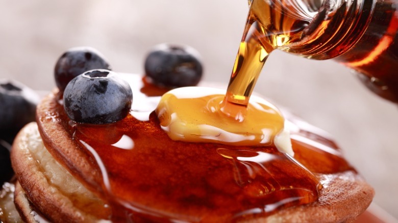 Maple syrup being poured on pancakes