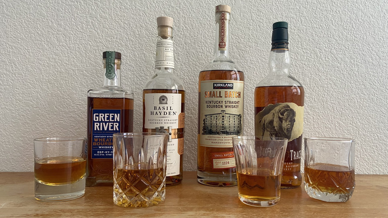 Four bourbon bottle's beside four half-full glasses
