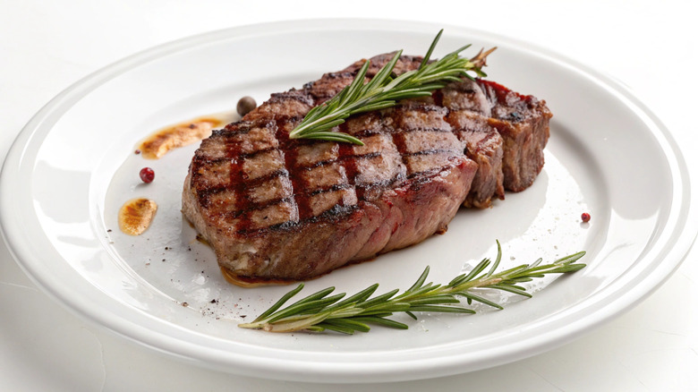 Steak on a white plate with rosemary sprigs