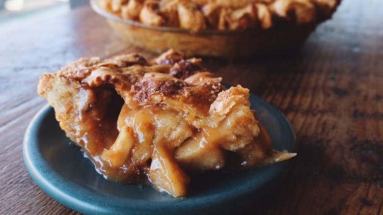 slice of apple pie on blue plate on wood table