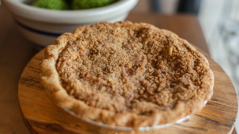 apple crumb pie on round wood cutting board