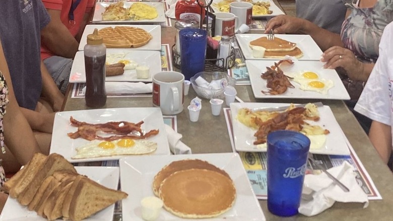 An array of breakfast egg dishes including pancakes and waffles on a large table.