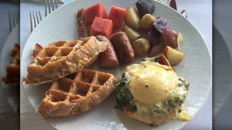 A plate of waffles, sausage, and egg.