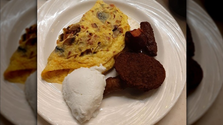 An omelet and sides from breakfast buffet on white plate.