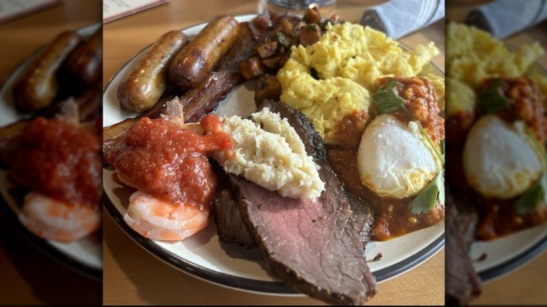 Home fries, bacon, sausage, and eggs, on a plate.