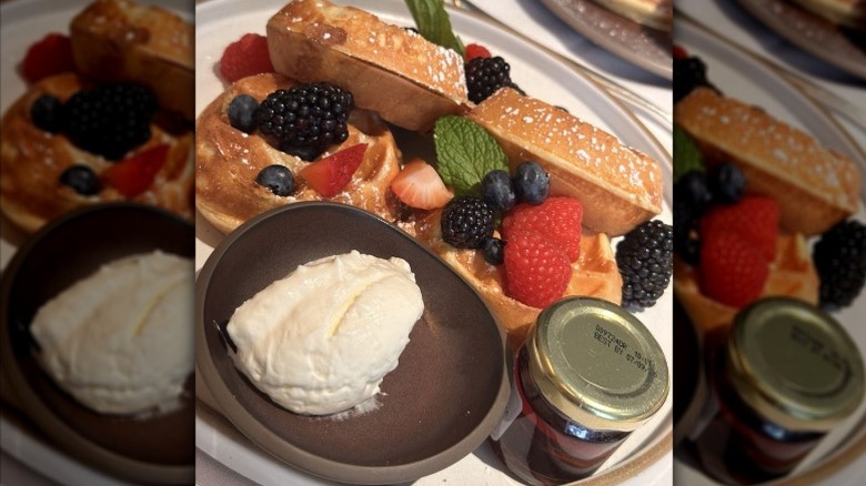 Waffles with berries, cream and syrup.