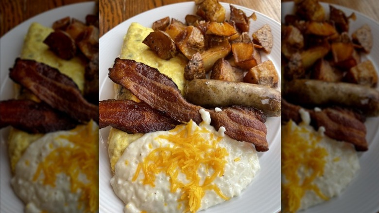 Grits, omelet, bacon, sausage, home fries on white plate.