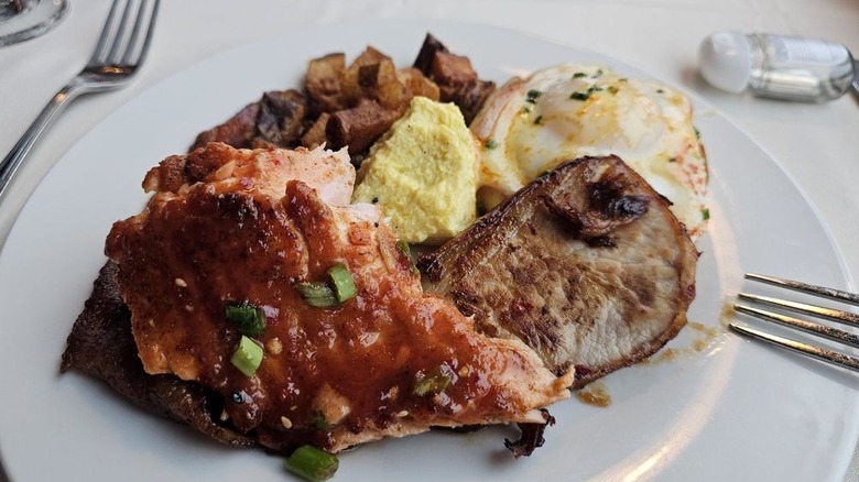 Home fries, eggs, and salmon on white plate.