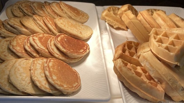 White trays of waffles and pancakes.