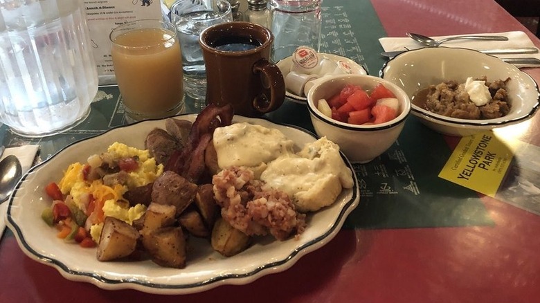Breakfast foods in diner-style plates and bowls, and beverages, on restaurant table.