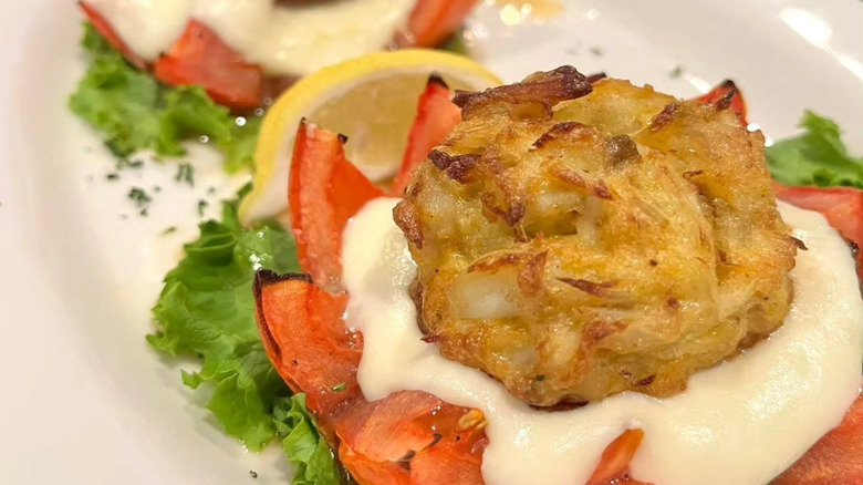 Crab cake with tomato and lemon wedge