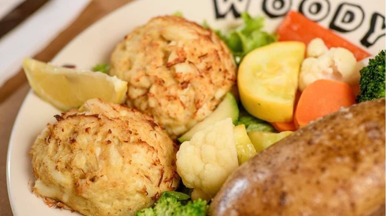 Two crab cakes and sides with lemon wedge