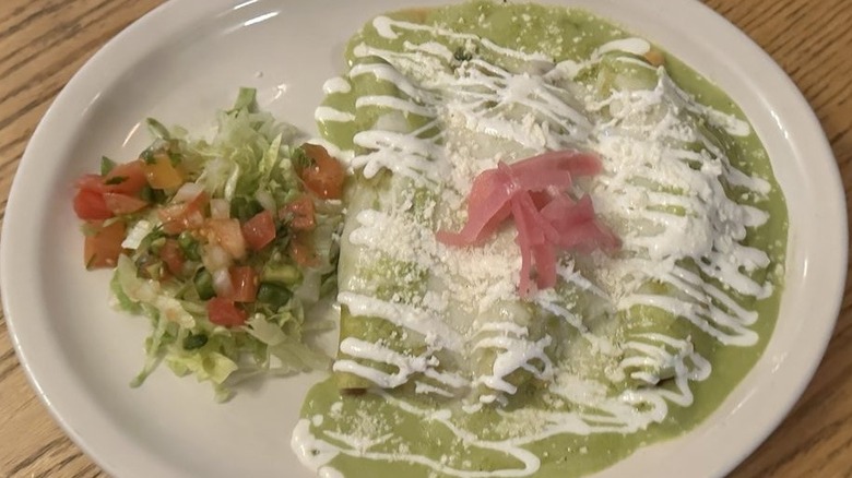 Three enchiladas verde drizzled with sour cream and queso fresco, garnished with pickled red onion; shredded lettuce and pico on the side