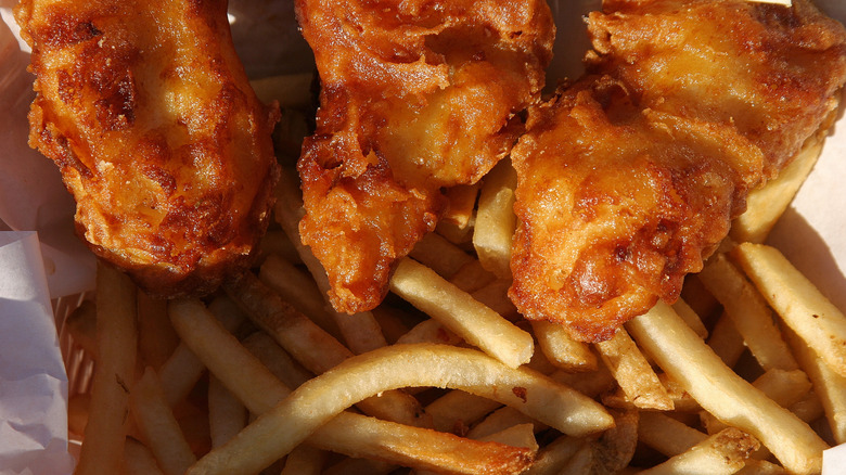 close up of fried fish and french fries in basket
