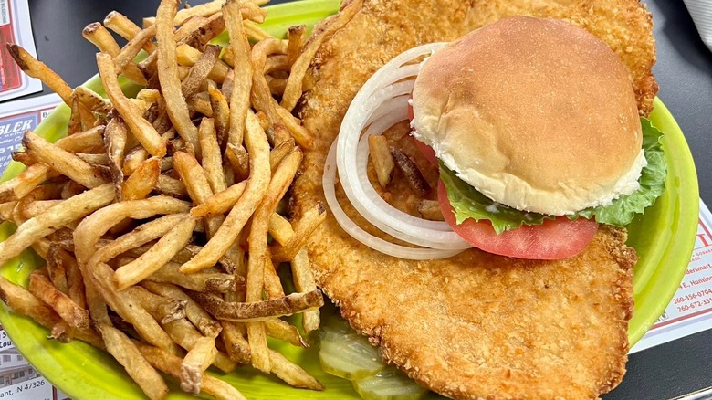 pork tenderloin sandwich with onions, tomato, lettuce and fries