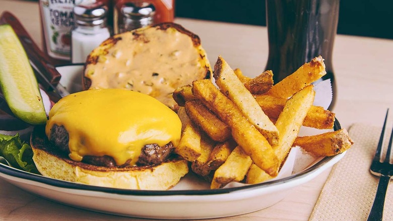 Cheeseburger with the bun lid removed and fries