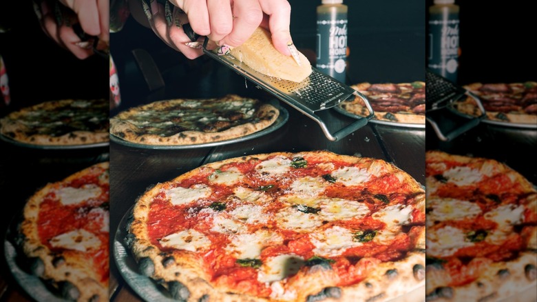A Pizza Bruno waitress grating Parmesan on top of a Margherita pizza