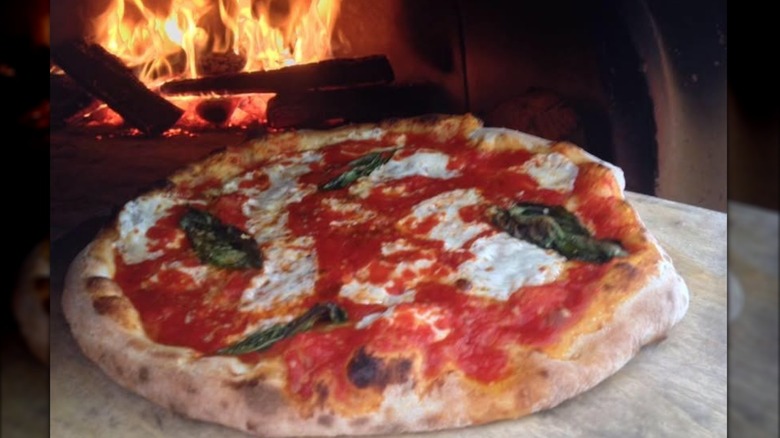 A Stoked Margherita pizza coming out of the wood-fired oven