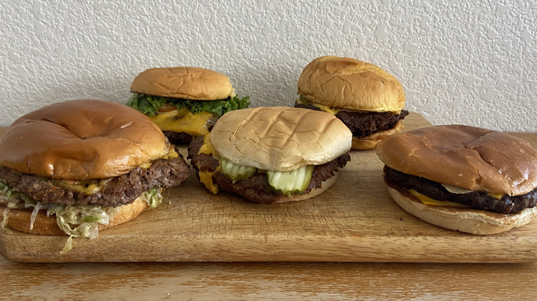 five smash burgers on a wooden cutting board