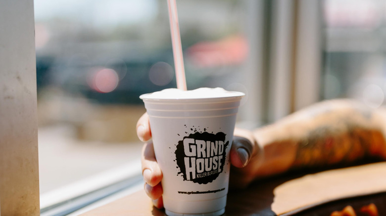 Tattooed arm holding Grindhouse milkshake cup.