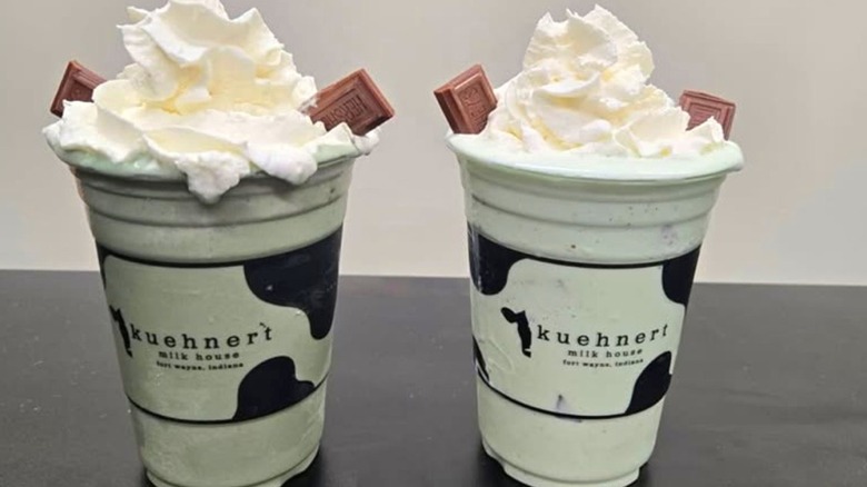 Two Kuehnert Milk House milkshakes topped with whipped cream and Hershey's chocolate bar segments.
