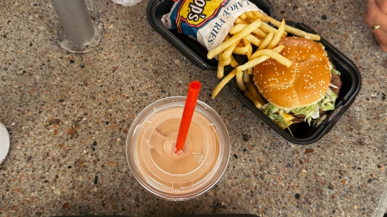 Aerial of B-Bop milkshake with red straw, burger and fries on a table.
