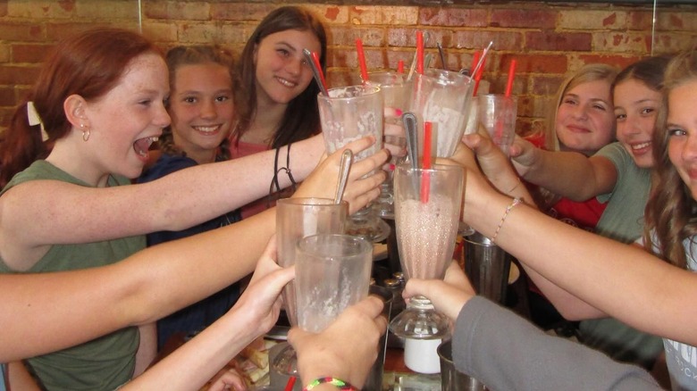 Milkshake toast with a group of smiling young girls.