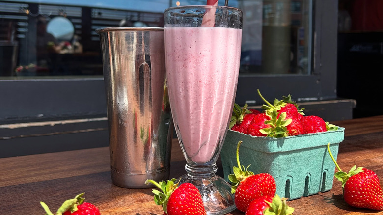 Strawberry milkshake at Duckfat, in glass with fresh strawberries next to it.