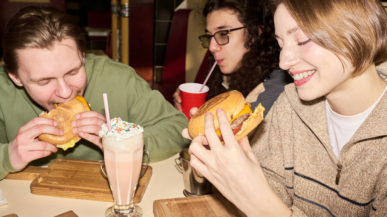 People enjoying milkshakes and burgers.