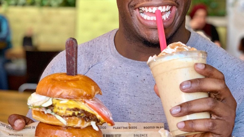 Man drinking cornflake shake, with burger.