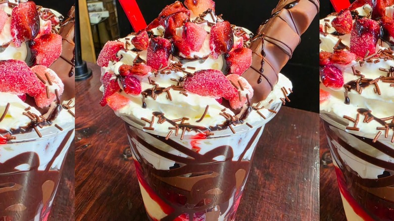 The top of a milkshake, with whipped cream, candies, and chocolates.