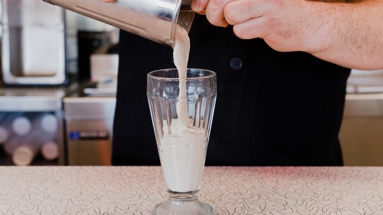 Milkshake being poured into glass.