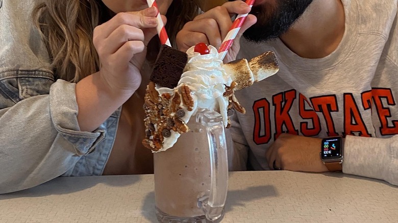 Couple sharing elaborate milkshake.