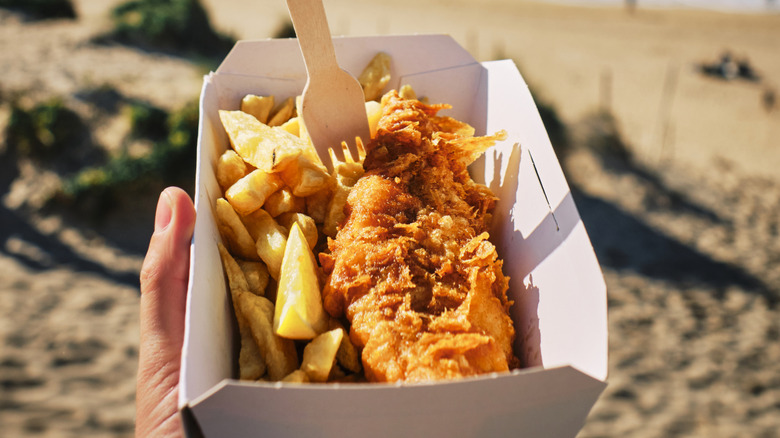 hand holding box of fish and chips