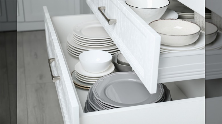 Open kitchen drawers with dinner plates stacked