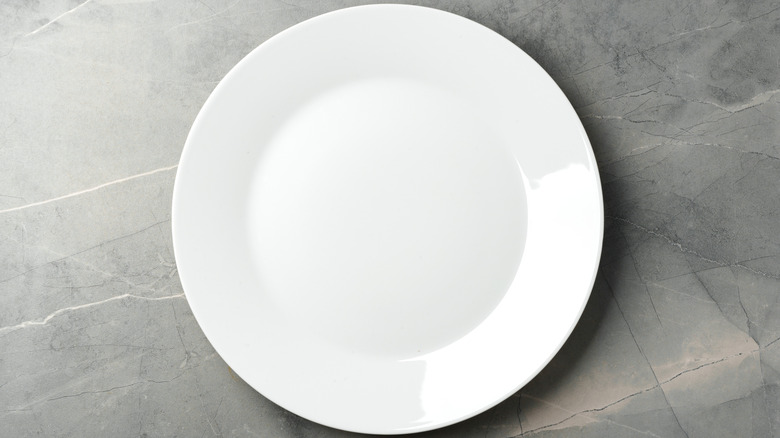 Empty white plate on gray background