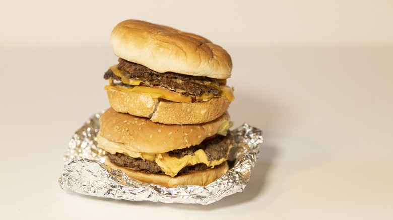 Two double-patty cheeseburgers from Five Guys sitting atop each other on a foil wrapper.
