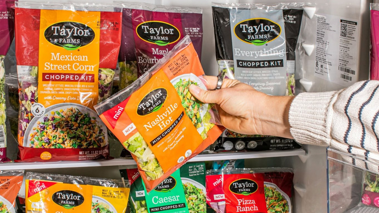 Various Taylor Farms salad kits in open refrigerator.