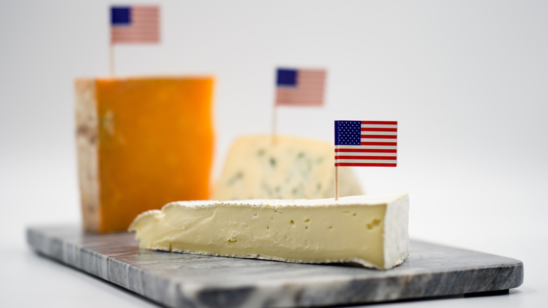 Cheeses marked with tiny American flags on cutting board