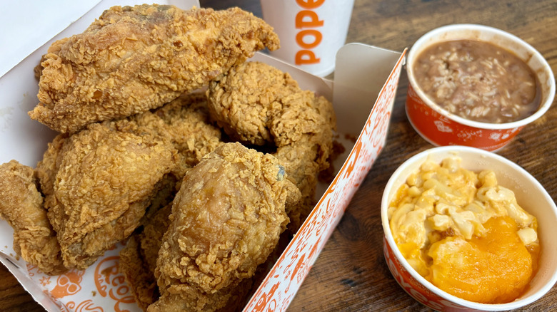 A box of Popeyes Signature chicken with a side of mac and cheese, beans and rice, and a drink