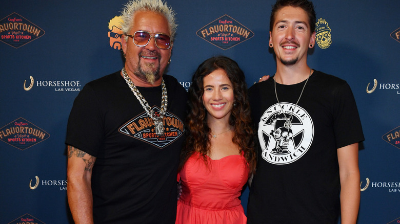 Guy Fieri, Tara Bernstein, and Hunter Fieri posing at Flavortown Sports Center.