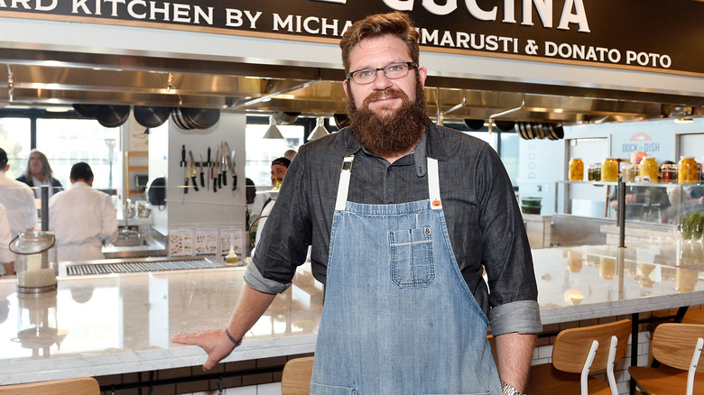Chef Michael Cimarusti poses in an apron in front of a restaurant counter space